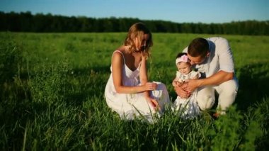 Mutlu bir aile. Baba Anne ve küçük bir kız, bir alanda yürüyüş batan güneşin ışınları altında beyaz giyinmiş