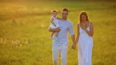 Parkta gün batımında mutlu yedi yürür. Beyaz giysiler, güneş, yaz.