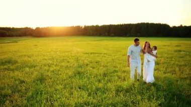 Parkta gün batımında mutlu yedi yürür. Beyaz giysiler, güneş, yaz.