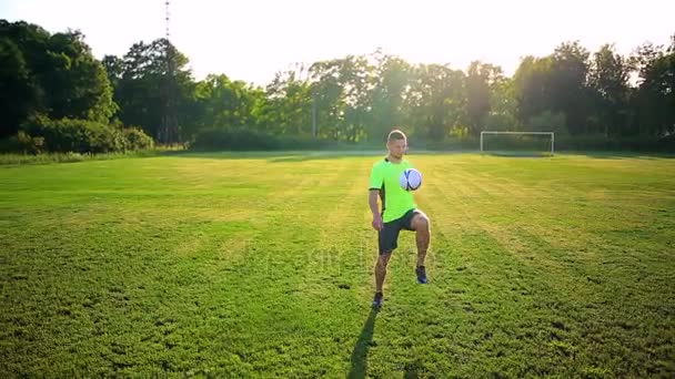 Člověk hrát fotbal na zelené louce na ráno. — Stock video