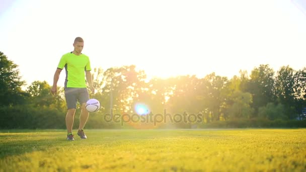 Člověk hrát fotbal na zelené louce na ráno. — Stock video