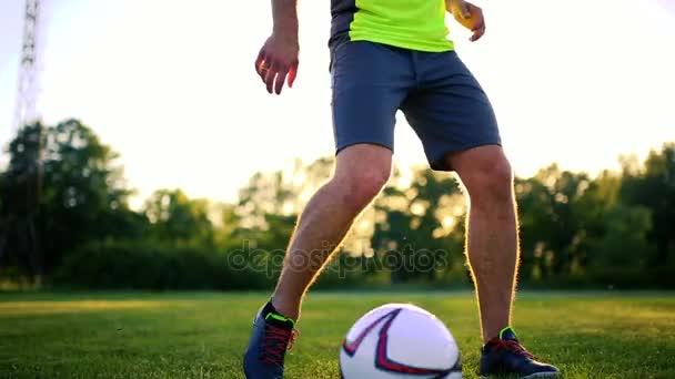Cerrar las piernas y los pies del jugador de fútbol en acción con zapatos negros corriendo y goteando con la pelota jugando en el campo de hierba verde aislado en el fondo negro — Vídeos de Stock