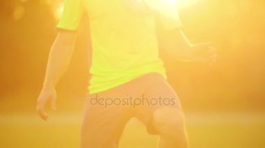 Profesyonel bir futbolcu ve yeşil Üniformalı erkeklere, diz futbol topu dengelemek.