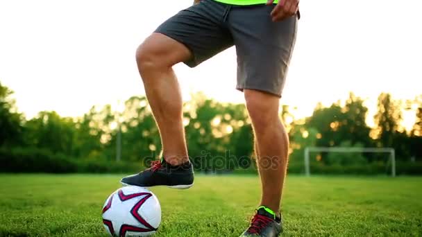 Cerrar las piernas y los pies del jugador de fútbol en acción con zapatos negros corriendo y goteando con la pelota jugando en el campo de hierba verde aislado en el fondo negro — Vídeos de Stock