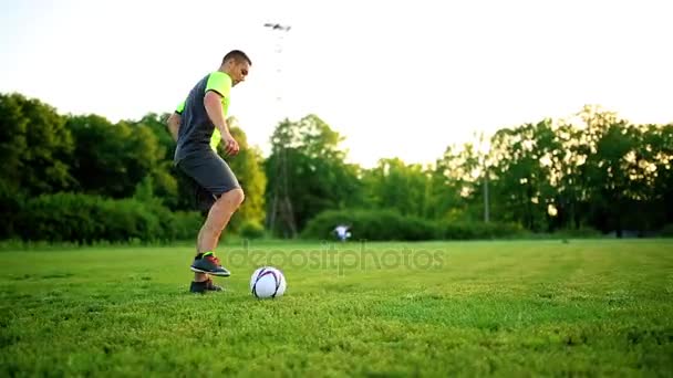 Cerrar las piernas y los pies del jugador de fútbol en acción con zapatos negros corriendo y goteando con la pelota jugando en el campo de hierba verde aislado en el fondo negro — Vídeo de stock