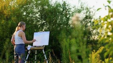 Coşku kızla boyalar bir kağıda bir manzara çizer.