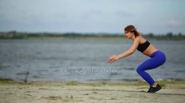 Güzel spor kız burpees akan Nehri yakınında sahilde atlama yok.