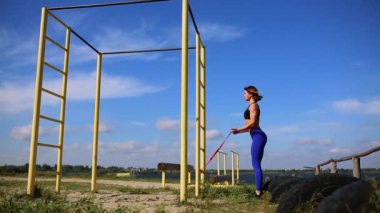 Lastikleri ile pazı egzersizleri yapıyor doğa kız. Nehri yakınında açık havada spor.