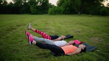 Abs kızlarına hissediyor. Grup yaz Park açık havada, yan görünüm yeşil çimenlerin üzerinde fiziksel egzersizleri yapıyor spor genç atletik insan