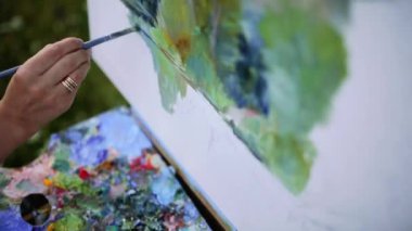 Güneşli yaz günde ekose parkta oturan ve beraberlik resim tarafından suluboya boya güzel bir manzara bitirme büyüleyici kadın