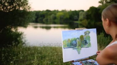 Coşku kızla boyalar bir kağıda bir manzara çizer.