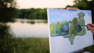 Coşku kızla boyalar bir kağıda bir manzara çizer.