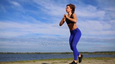 Koşucu kadın bacak egzersizleriyle bacaklarını esnetiyor. Fitness bayan sporcusu sahilde dinleniyor. Güç antrenmanından önce ısınıyor..