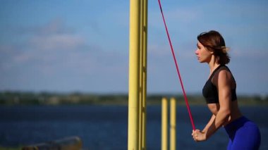 Esmer Nehri banka üzerinde mavi tozluk triceps bir lastik bant egzersizleri gerçekleştirir.