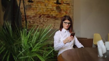 Güzel gülümseme kafede, onun resmi hücre telefon için serbest zaman sırasında kafede dinlenirken izlerken mutlu beyaz kadın dinlenme sırasında cep telefonu üzerinde iyi haber okuma ile büyüleyici kadın.