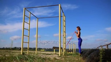 Lastikleri ile pazı egzersizleri yapıyor doğa kız. Nehri yakınında açık havada spor.