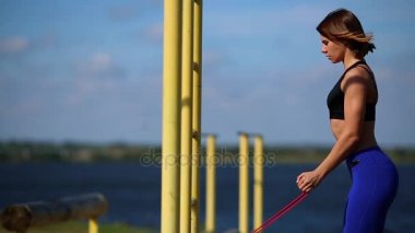 Lastikleri ile pazı egzersizleri yapıyor doğa kız. Nehri yakınında açık havada spor.