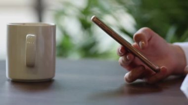 Kadının el cep telefonuyla kahve molası yakın çekim