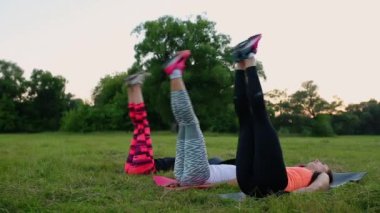 Abs kızlarına hissediyor. Grup yaz Park açık havada, yan görünüm yeşil çimenlerin üzerinde fiziksel egzersizleri yapıyor spor genç atletik insan