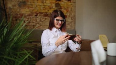 Güzel gülümseme kafede, onun resmi hücre telefon için serbest zaman sırasında kafede dinlenirken izlerken mutlu beyaz kadın dinlenme sırasında cep telefonu üzerinde iyi haber okuma ile büyüleyici kadın.