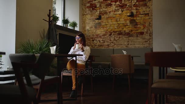 Smartphone meisje met behulp van app op de telefoon drinken koffie glimlachend in café. mooie multiculturele jonge casual vrouwelijke professional op mobiele telefoon. gemengd ras Aziatische Kaukasische model. — Stockvideo