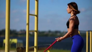 Lastikleri ile pazı egzersizleri yapıyor doğa kız. Nehri yakınında açık havada spor.