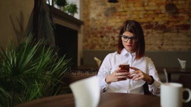 Güzel gülümseme kafede, onun resmi hücre telefon için serbest zaman sırasında kafede dinlenirken izlerken mutlu beyaz kadın dinlenme sırasında cep telefonu üzerinde iyi haber okuma ile büyüleyici kadın.
