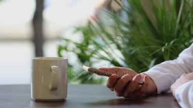 Yakın çekim. Kız cep telefonu ve iş ortağına konuşurken gülümser telefon rehberindeki gerekli kişiyi seçer.