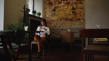 kafede kahve içme telefon üzerinde app gülümseyen kullanan akıllı kız. güzel kültürlü genç casual kadın profesyonel üstünde hareket eden telefon. karışık ırk asian beyaz modeli.