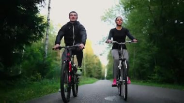 Yakışıklı erkek profesyonel bisikletçi kız arkadaşı, her iki giyiyor Koruyucu baretler birlikte sabah onun yarış bisiklet sürme sakallı ve gözlük, güneş aralarında parlıyor.