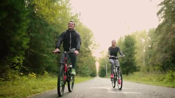 Приваблива пара, що йде з велосипедами і питною водою в лісі — стокове відео