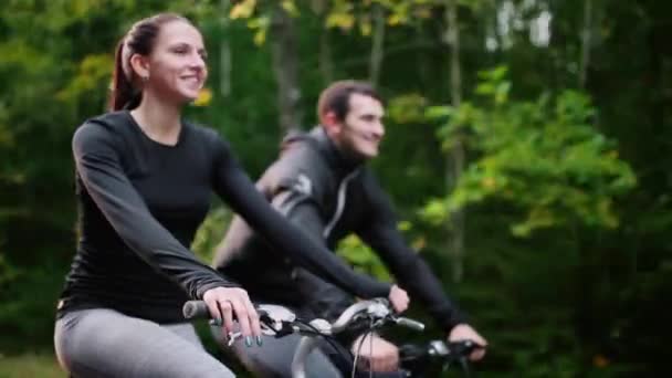 Jeune couple profitant du vélo à travers le parc en été — Video