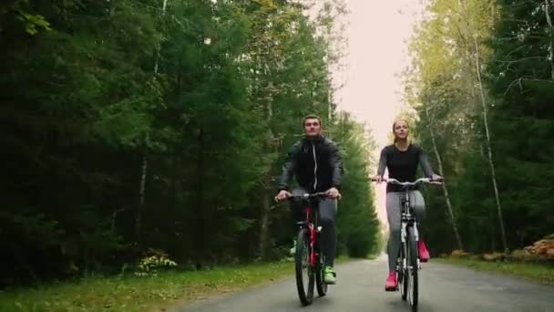 Atractiva pareja caminando con bicicletas y agua potable en el bosque — Vídeos de Stock