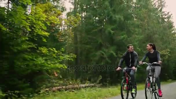 Atractiva pareja caminando con bicicletas y agua potable en el bosque — Vídeos de Stock