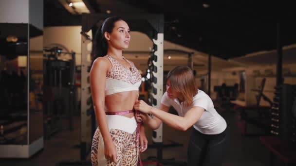 Female personal trainer has been measuring waist, bust, and hips for female who wants to lose weight. — Stock Video