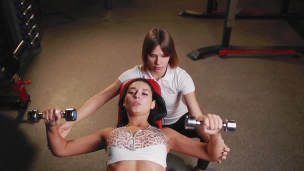 Femme avec son entraîneur de fitness personnel dans la salle de gym exercice avec haltères . — Video