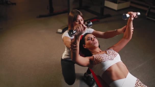 Mulher com seu personal fitness trainer no ginásio exercitando com halteres . — Vídeo de Stock