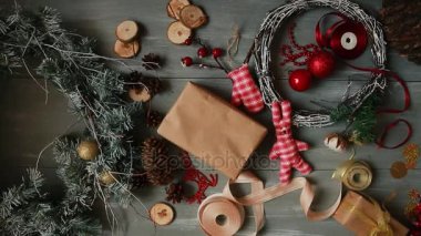 Tepe-aşağı planı. Tamamen görünür tablo süslemeler ile. Eller koymak ve Noel sonuçlandırmak ahşap bir masa craftool kağıda sarılmış hediye. Bant sarmak ve bir yay bağlı.