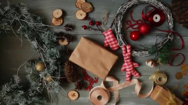 Tepe-aşağı planı. Tamamen görünür tablo süslemeler ile. Eller koymak ve Noel sonuçlandırmak ahşap bir masa craftool kağıda sarılmış hediye. Bant sarmak ve bir yay bağlı.