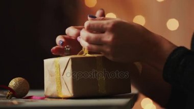 Arka plan Christmas yakın çekim şerit Kraft kağıt hediye ipe kadın eller ışıkları. Bokeh arka plan bulanık.
