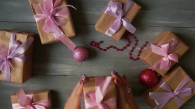 Tepe-aşağı planı. Tamamen görünür tablo süslemeler ile. Eller koymak ve Noel sonuçlandırmak ahşap bir masa craftool kağıda sarılmış hediye. Bant sarmak ve bir yay bağlı.