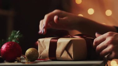 Arka plan Christmas yakın çekim şerit Kraft kağıt hediye ipe kadın eller ışıkları. Bokeh arka plan bulanık.