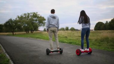 genç adam ve kadın parkta Hoverboard sürme. içerik teknolojileri. yeni bir hareket. Çift tekerleğin kendini elektrik kaykay akıllı Dengeleme kapatın. açık havada elektrikli scooter üzerinde.