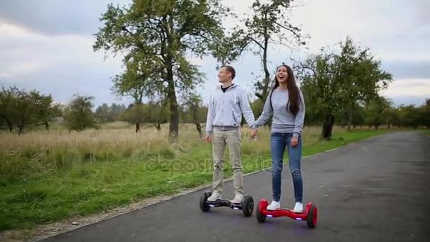 Joven hombre y mujer cabalgando en el Hoverboard en el parque. tecnologías de contenido. un nuevo movimiento. Primer plano de Dual Wheel Self Balancing Electric Skateboard Smart. en scooter eléctrico al aire libre . — Vídeo de stock
