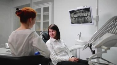 Güzel kız ofis topunu dişlerini için işaret ağrı timus üzerinde bir doktor danışılmalıdır. Beyaz, steril doktorlar ofisi. Ekran diş röntgen ağız boşluğunda gösterir.