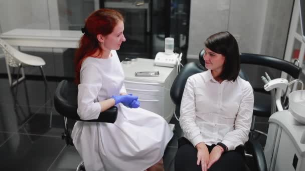 Bella ragazza consultato un dentista nel suo studio palla sul timo del dolore che punta i denti. Bianco, ufficio medici sterili . — Video Stock