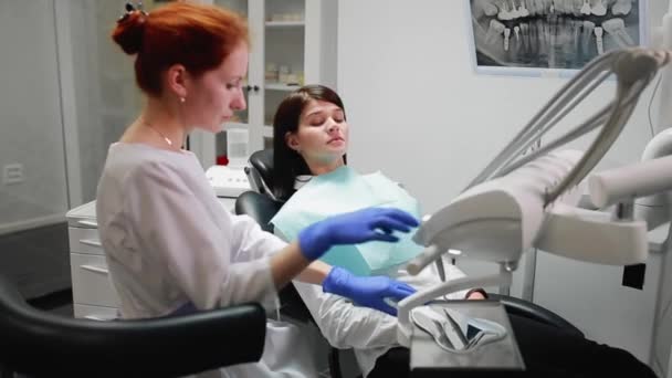 Стоматолог завершує роботу з пацієнтом. Вилучає машину Бор і дає дівчині дзеркало для оцінки роботи. Дівчина дивиться на зуби і дякує стоматологу . — стокове відео