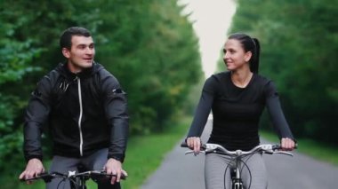 Yakışıklı erkek profesyonel bisikletçi kız arkadaşı, her iki giyiyor Koruyucu baretler birlikte sabah onun yarış bisiklet sürme sakallı ve gözlük, güneş aralarında parlıyor.