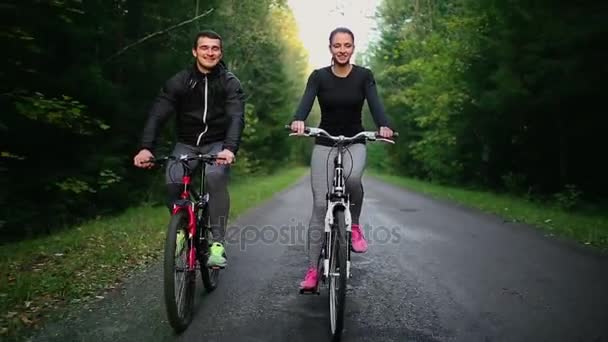 Gelukkige jonge paar - man en vrouw - fietsen in de zomer in de natuur — Stockvideo