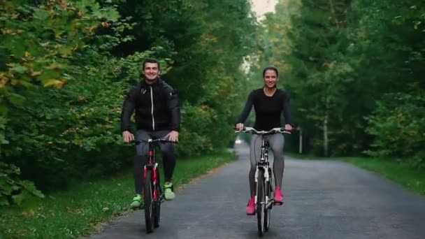 帅胡子专业踏单车的男子和他的女友，两个穿着的防护头盔早上骑赛车自行车和眼镜，太阳照耀着他们之间. — 图库视频影像